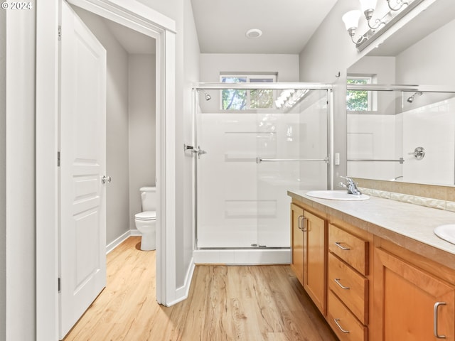 bathroom with wood-type flooring, vanity, toilet, and an enclosed shower