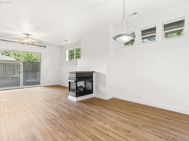 unfurnished living room featuring a multi sided fireplace, hardwood / wood-style floors, and ceiling fan