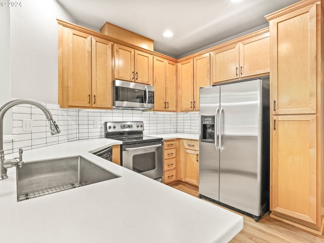 kitchen with light brown cabinets, light wood-type flooring, sink, and appliances with stainless steel finishes