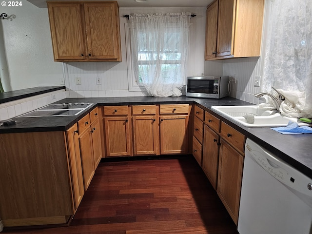 kitchen with kitchen peninsula, sink, white dishwasher, and dark wood-type flooring