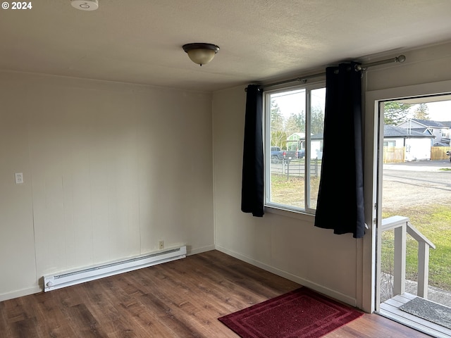 interior space with baseboard heating, a wealth of natural light, and hardwood / wood-style flooring