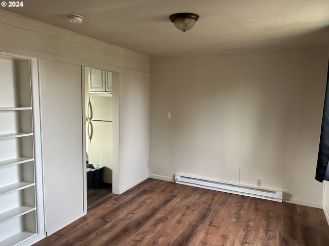 unfurnished bedroom featuring dark hardwood / wood-style floors, ensuite bath, and a baseboard heating unit