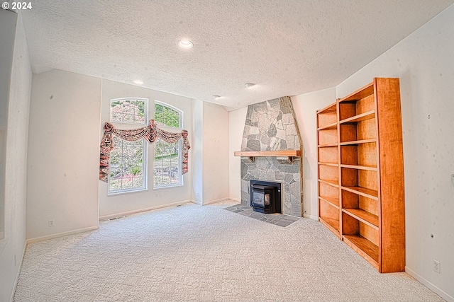 unfurnished living room with vaulted ceiling, a fireplace, a textured ceiling, and carpet floors