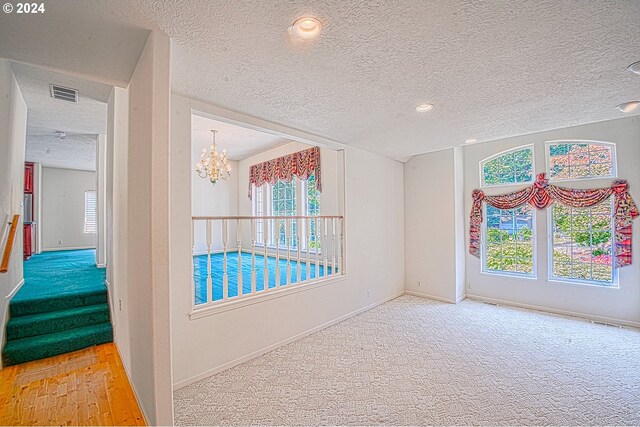 spare room with carpet, a textured ceiling, and a chandelier