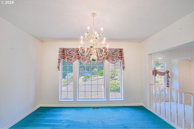 interior space featuring a wealth of natural light, carpet flooring, a textured ceiling, and an inviting chandelier