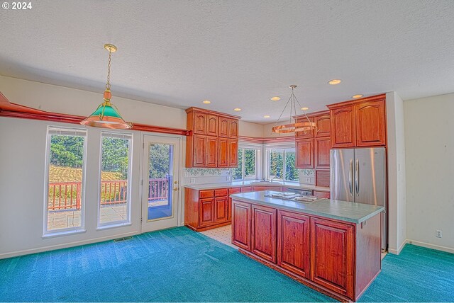 kitchen featuring a center island, sink, decorative light fixtures, stainless steel refrigerator, and light carpet