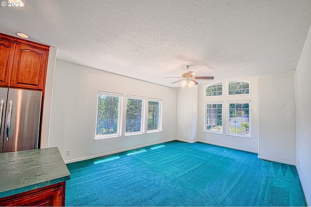 empty room featuring dark carpet, ceiling fan, and a textured ceiling