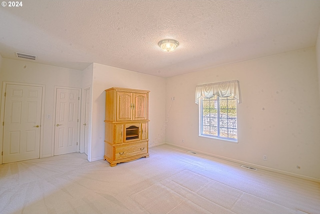 carpeted empty room featuring a textured ceiling