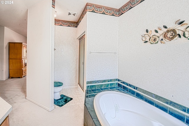 bathroom with tile patterned floors, a textured ceiling, tiled tub, vanity, and toilet