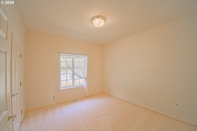 carpeted empty room with a textured ceiling