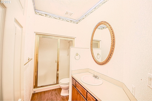 bathroom featuring toilet, vanity, hardwood / wood-style floors, a textured ceiling, and a shower with shower door