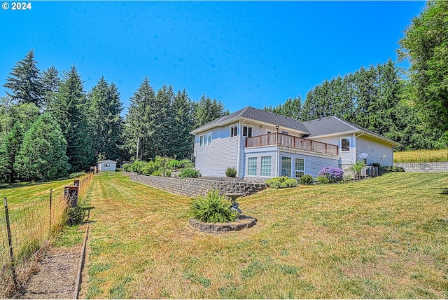 view of side of property with a storage unit, a yard, and a balcony