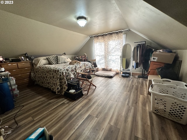 bedroom featuring hardwood / wood-style flooring, vaulted ceiling, and a textured ceiling