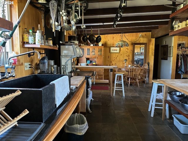 kitchen with wood walls, beamed ceiling, and sink