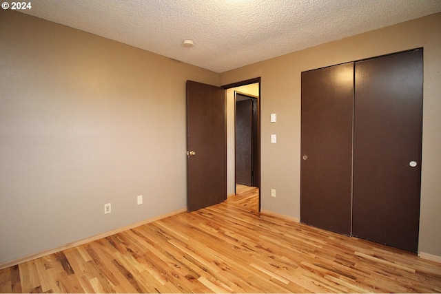 unfurnished bedroom featuring a textured ceiling, light hardwood / wood-style floors, and a closet