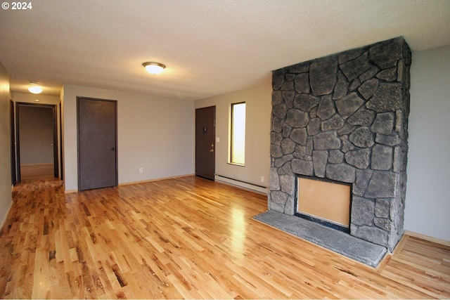 unfurnished living room with a fireplace, light wood-type flooring, a textured ceiling, and a baseboard heating unit