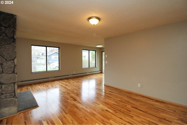 spare room with a baseboard heating unit, light hardwood / wood-style floors, and a textured ceiling