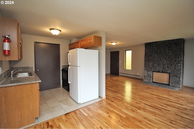 kitchen with a fireplace, sink, white fridge, baseboard heating, and black range with electric cooktop