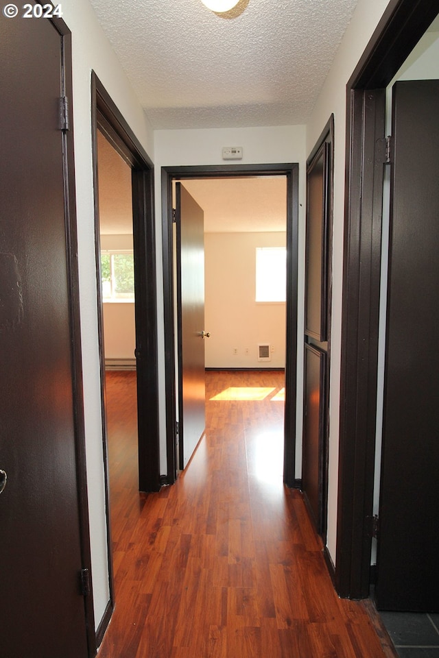 hall with dark hardwood / wood-style floors and a textured ceiling