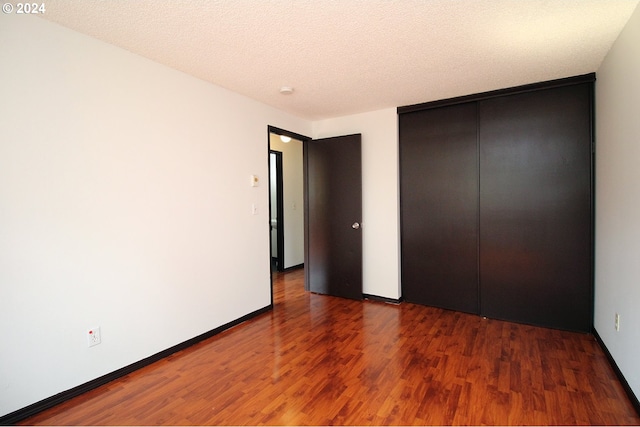 unfurnished bedroom with dark hardwood / wood-style floors, a closet, and a textured ceiling