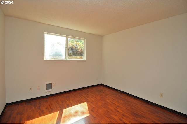 spare room featuring hardwood / wood-style floors and a textured ceiling