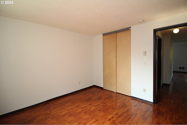 unfurnished bedroom featuring dark hardwood / wood-style floors, a textured ceiling, and a closet