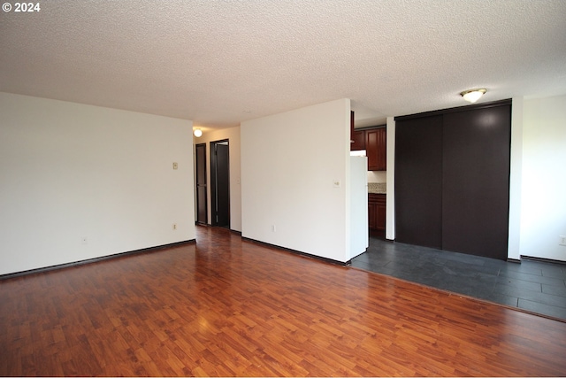 unfurnished room with dark hardwood / wood-style flooring and a textured ceiling