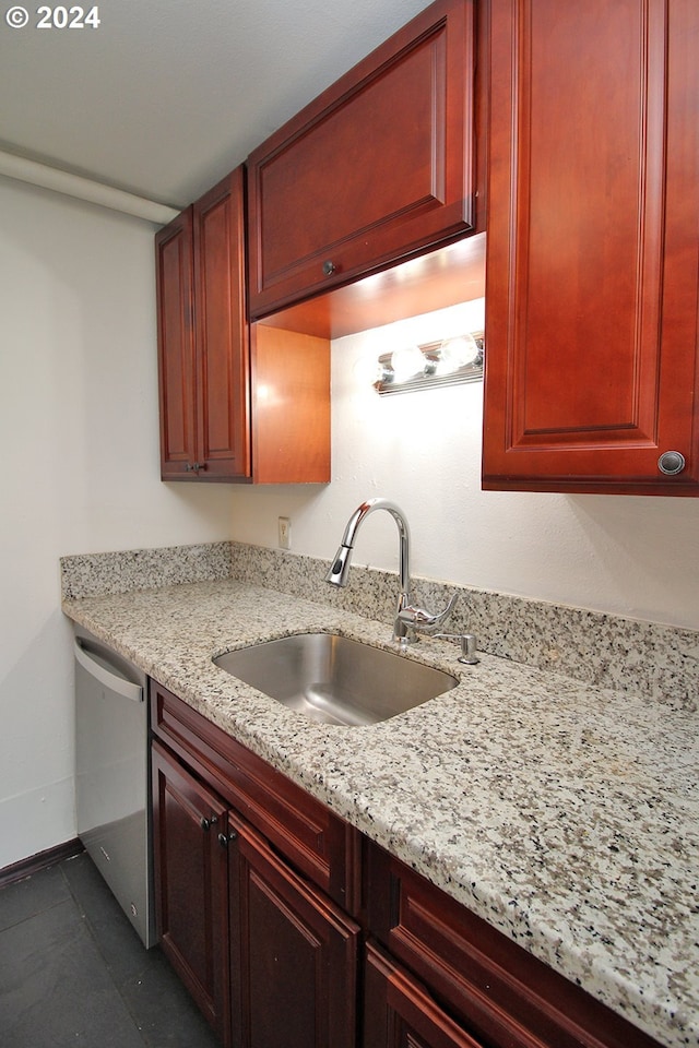 kitchen with stainless steel dishwasher, light stone countertops, and sink