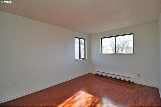 spare room featuring dark hardwood / wood-style floors, a textured ceiling, and a baseboard heating unit