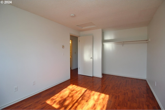 unfurnished bedroom featuring dark wood-type flooring, a textured ceiling, and a closet