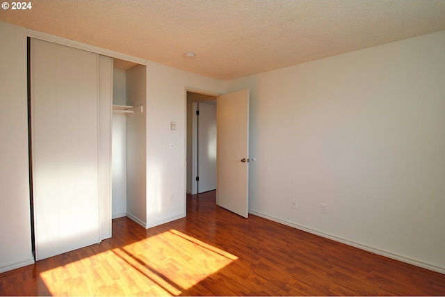 unfurnished bedroom featuring wood-type flooring, a textured ceiling, and a closet