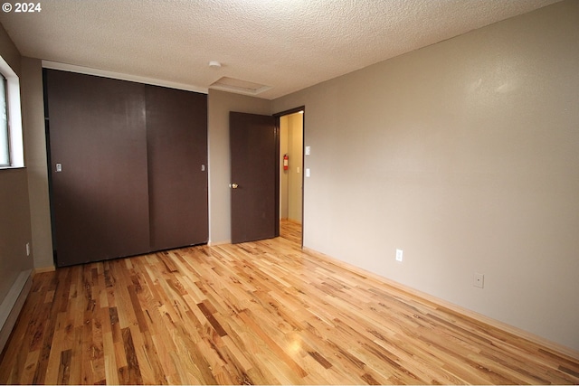 unfurnished bedroom featuring a closet, a textured ceiling, and light wood-type flooring