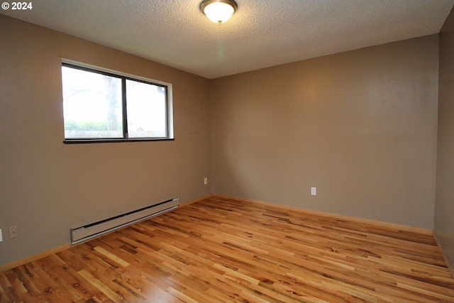 empty room with a baseboard heating unit, light hardwood / wood-style flooring, and a textured ceiling