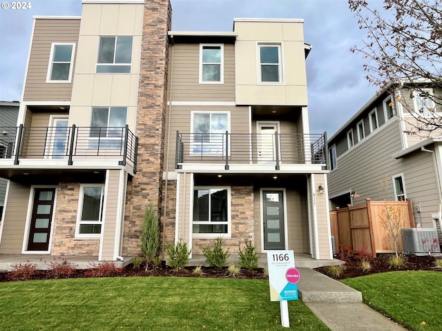 view of front facade featuring cooling unit, a balcony, and a front lawn