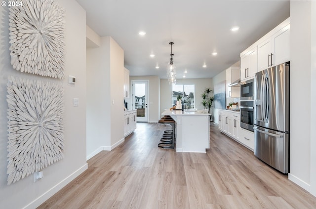 kitchen featuring stainless steel appliances, white cabinets, and a center island with sink