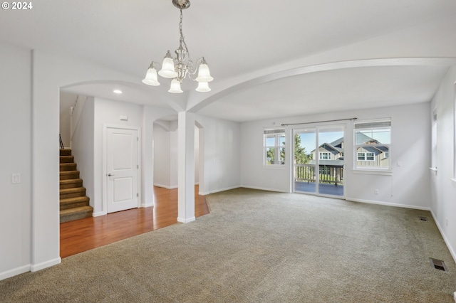 carpeted empty room featuring a notable chandelier