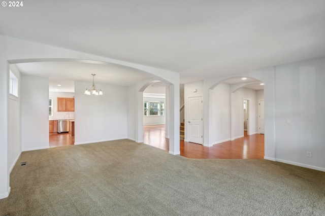 unfurnished living room with a notable chandelier and light carpet