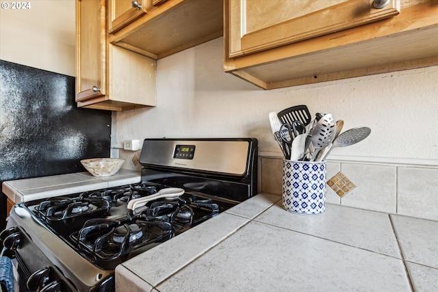 details featuring black range with gas stovetop and tile counters