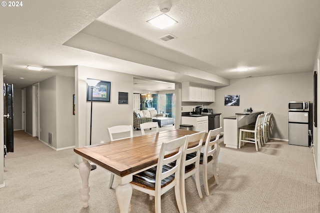 carpeted dining space featuring a textured ceiling