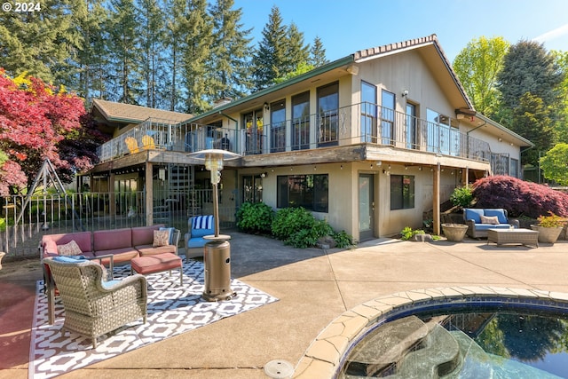 rear view of house with a patio area, outdoor lounge area, and a balcony