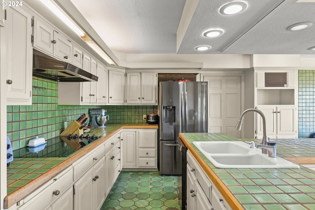 kitchen with tasteful backsplash, tile floors, white cabinetry, tile counters, and sink