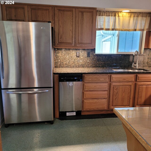 kitchen with dark stone countertops, sink, decorative backsplash, and stainless steel appliances