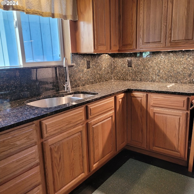 kitchen featuring sink, backsplash, and dark stone counters