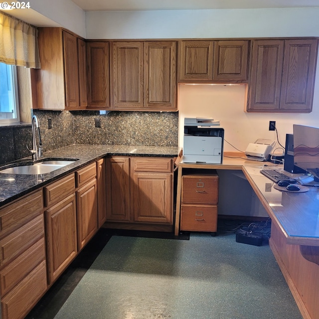 kitchen featuring tasteful backsplash, dark stone counters, and sink