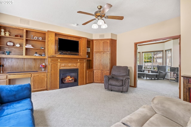 carpeted living area featuring ceiling fan and a glass covered fireplace