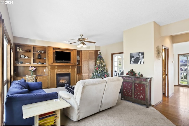 living room with ceiling fan, light hardwood / wood-style floors, and a textured ceiling