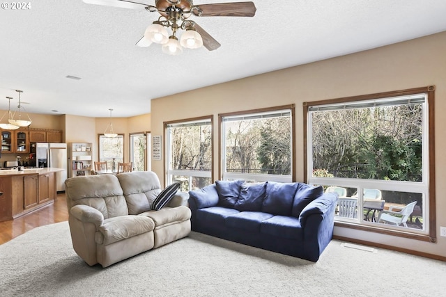 living room with a textured ceiling, light hardwood / wood-style flooring, and ceiling fan