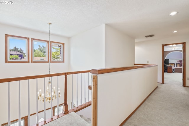 hall featuring light carpet, a chandelier, recessed lighting, an upstairs landing, and a textured ceiling