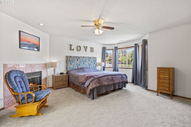 carpeted bedroom with a textured ceiling, ceiling fan, and a tile fireplace