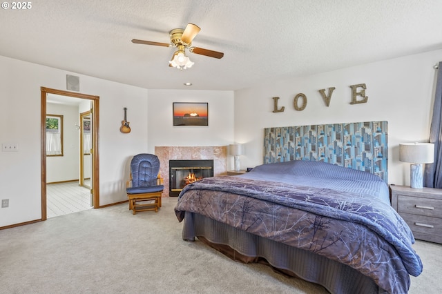 bedroom featuring carpet flooring, a tile fireplace, baseboards, a textured ceiling, and a ceiling fan